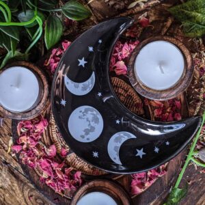 This small moon phase candle plate is a perfect addition to any altar or shrine! A perfect size for chime candles, tealights, as well as crystals, cleansing salts and offerings. This candle plate is an excellent accompaniment for any witchcraft or devotional working. Of course, with it's moon phase print, you may wish to reserve it for more lunar magic more than other types of witchcraft. Ways of Working There's plenty of room for a main candle on this plate, as well as offering and petitions for any spirit working you may wish to do. This could become in essence a moveable shrine within itself. Simply light a candle and then place any other offerings you wish upon the plate.  With the Lunar print, you may wish to reserve this plate for lunar workings- anything done to honour or work with the moon. This could be a wonderful dish to use to lay out your crystals and other objects under the full moon. Whatever you wish to be blessed or infused in moonlight, place it on this dish and then leave it under the moon's rays. Because of it's size, this can also be a wonderful cleansing dish. Simply fill it with salts, or cleansing herbs of your choice and then lay on any objects on top that you wish to be cleansed.  And of course, this is the perfect size dish for 'grab and go' crystals. Place your favourite crystals in this dish on your altar for easy access. 